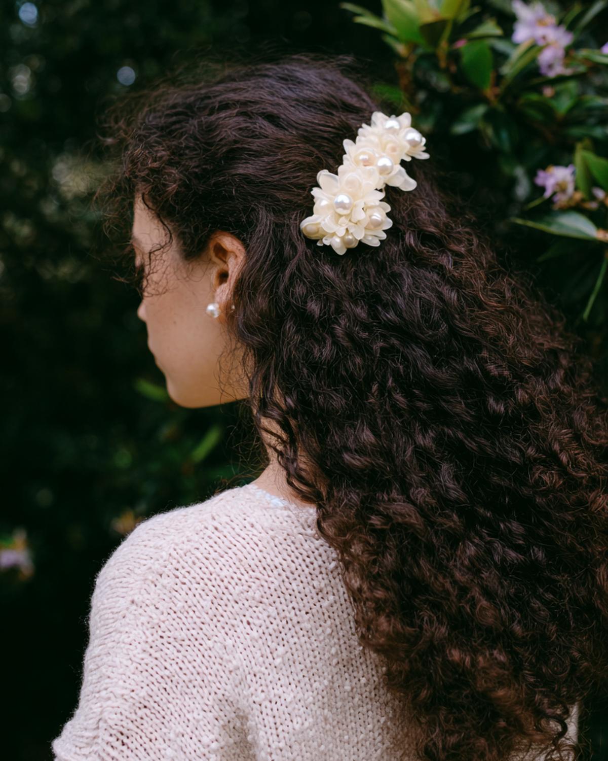 4. Demi-attache romantique en cheveux bouclés naturellement coiffure avec pince nacrée et texture floue